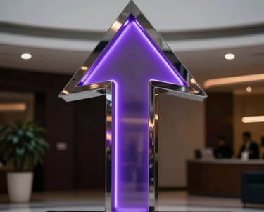 A sharp, modern photograph of a polished metal sculpture representing an upward arrow, reflecting purple neon lights in a dark, professional lobby in Latinoamérica.