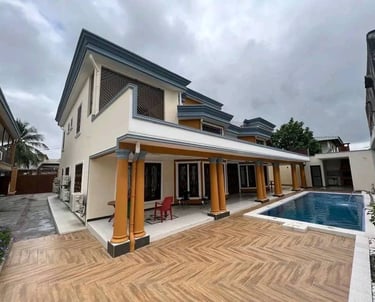Modern two-story villa with a luxury outdoor swimming pool and wood-tiled patio under a cloudy sky.