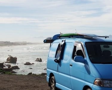 a van parked on the beach with surfboards on the beach