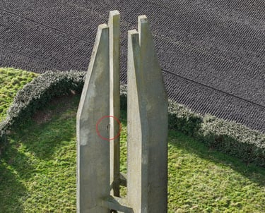 Gros plan d'un pilier de monument en béton avec un petit trou encerclé en rouge pour inspection.