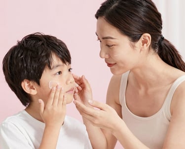Una madre aplica una crema hidratante suave en el rostro de su hijo pequeño como parte de su rutina 