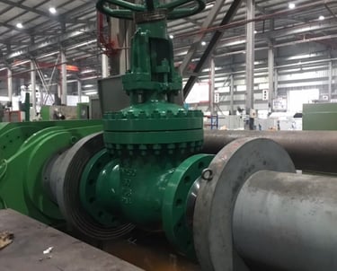 Large green industrial gate valve installed on a steel pipeline inside a manufacturing facility.