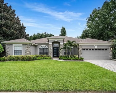 Exterior of a single-story home with a front lawn, stone accents, and an attached garage.