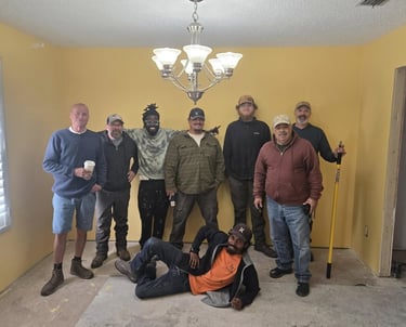Members of the Suwannee Sunshine Services crew standing together inside a home during a project.