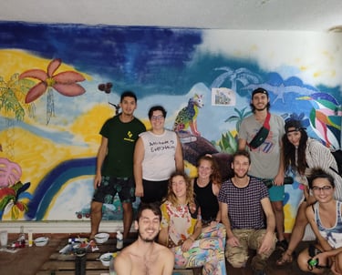 Un groupe de bénévoles de divers horizons pose devant une fresque murale tropicale colorée