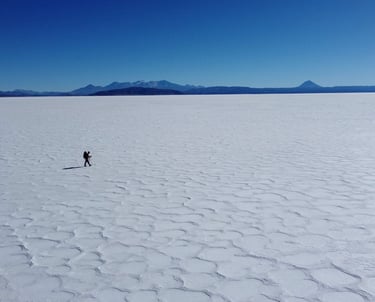 Un randonneur solitaire marche à travers l’immensité blanche du salar d’Uyuni en Bolivie