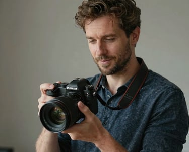 Portrait of a Southern European man holding a professional camera in a studio setting. Natural lighting, sophisticated and approachable vibe.