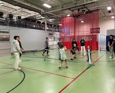 Children and QLeague Kids staff play an adaptive volleyball game in a gymnasium