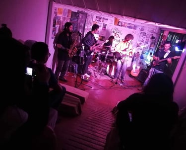 Banda en vivo interpretando jazz fusión en un escenario pequeño con iluminación púrpura y el público