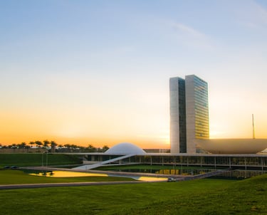 Vista panorâmica do Congresso Nacional do Brasil iluminado pelo pôr do sol, símbolo do comitê de sim