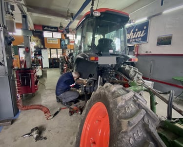 ένας μηχανικός τρακτέρ επισκευάζει ένα τρακτέρ με κουβούκλιο μέσα στο συνεργείο - kotsou tractors