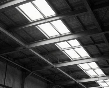 A minimal black and white photo of an industrial warehouse in Germany, focusing on the geometric patterns of the ceiling structure and natural light.