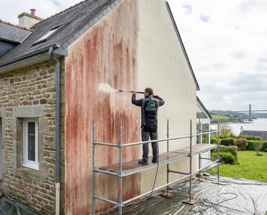 Artisan façadier nettoyant les algues rouges sur le pignon d'une maison à Plougastel-Daoulas (29470)