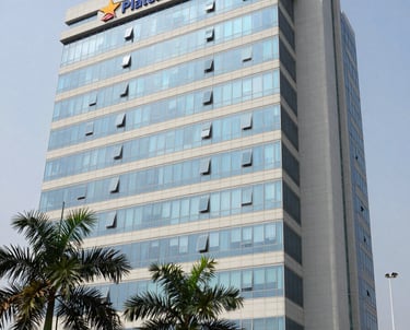 A prestigious office building in Plateau, Abidjan, representing the headquarters of a conglomerate, featuring glass architecture, pale gray-white facade, and palm trees in the foreground, professional lighting.