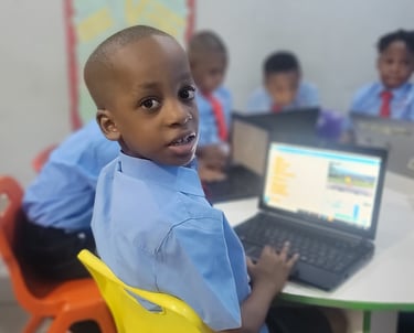 A 5 year old boy coding with his classmates in his classroom