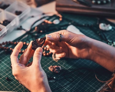 mujer creando collares a mano con piedras
