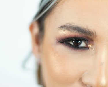 Primer plano de un glamoroso maquillaje de ojos con brillo dorado, sombra de ojos ahumada y pestañas