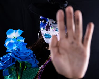 Mujer con maquillaje de calavera de azúcar del Día de Muertos sosteniendo rosas azules }