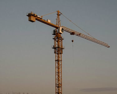 Professional photography of a construction site featuring a massive gold-painted crane against a graphite grey sunset sky.