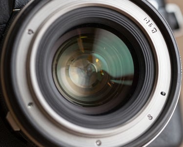 A macro shot of a camera lens showing the internal glass elements and brushed silver body. High-end engineered feel, industrial precision.