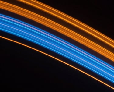 Abstract close-up of light painting in a dark studio, creating cinematic streaks of orange and blue. Representing creativity and innovation.