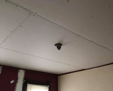 new drywall hung on ceiling of home with wood trim