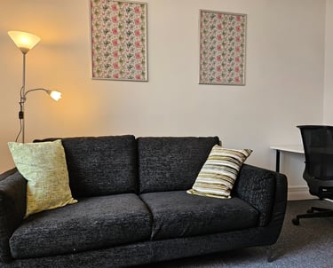 Modern counselling room featuring a charcoal gray fabric sofa with decorative pillows