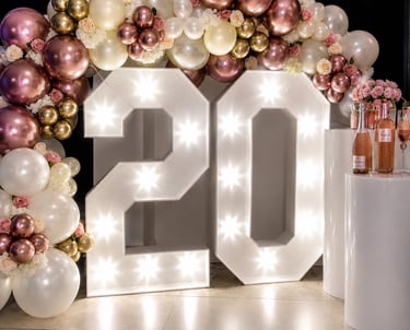 Large white marquee number 20 display with rose gold and gold balloon arch for a birthday celebration.