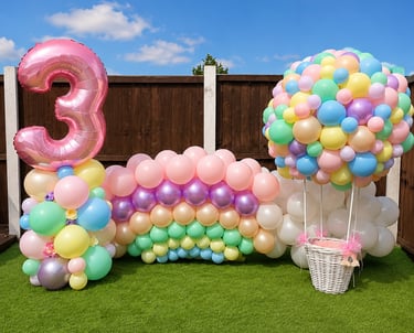Pastel rainbow balloon arch with pink number three and hot air balloon decoration for 3rd birthday party.
