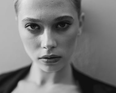 Black and white close-up portrait of a woman with intense eyes and professional makeup.