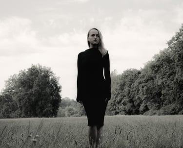 Portret kobiety na łące w tle drzewa, czerń i biel