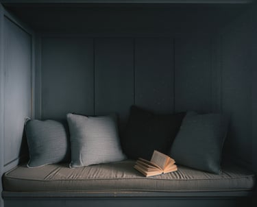 An over-decorated bench nook crowded with pillows and wall decor, cluttered feel.