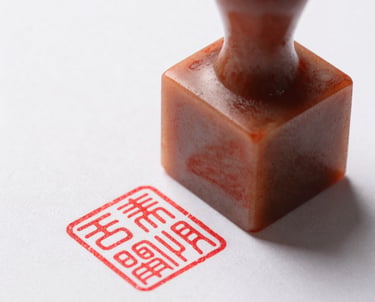 Macro shot of a red ink seal (Hanko) on a white document. Sharp focus, high contrast, clean and professional.