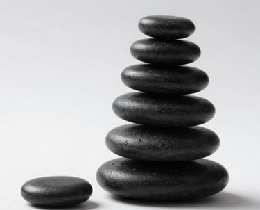 A stack of smooth black stones balanced perfectly on a white surface. Soft light from the side, extreme minimalism.