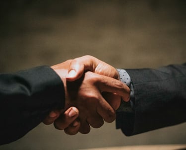 two people shaking hands over a wooden table