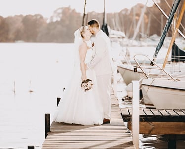 Brautpaar küsst sich auf einem Steg am Möhnesee bei Sonnenlicht – romantischer Moment eingefangen vom Hochzeitsfotografen am 