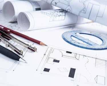 A set of building plans with pen, pencil and a pair of compasses