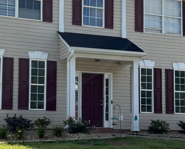 After overgrown shrubs were removed smaller shrubs were installed and windows of house are now visible.