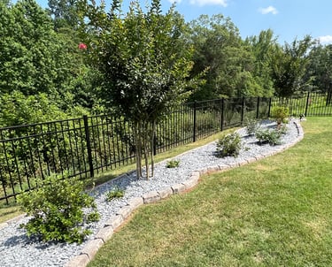 Created backyard flowerbed along the black fence with azaleas, butterfly bushes, roses, slate mulch and stone border.