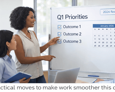 A diverse small business team meets in a modern office, reviewing a “Q1 Priorities” whiteboard.