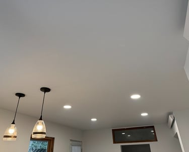 Modern white kitchen ceiling featuring recessed LED lights and two glass pendant light fixtures.