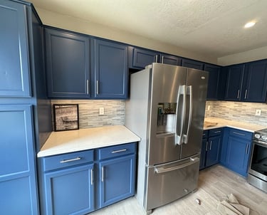 Modern kitchen with blue painted cabinets, white quartz countertops, and stainless steel appliances.