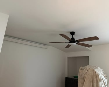 Modern 5-blade wooden ceiling fan with integrated light installed in a white room.