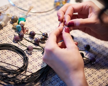 Artista de joyería hecha a mano ensarta cuentas de vidrio en un cordón para crear joyeria artesanal