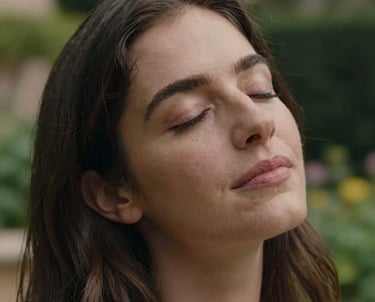 A close-up portrait of a woman with a gentle expression, eyes closed in a moment of peace, outdoor lighting in a Spanish garden, professional photography, empathetic atmosphere.