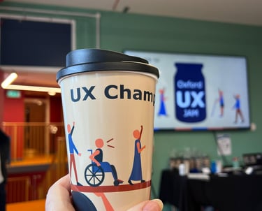 A reusable coffee cup featuring inclusive UX design illustrations at an Oxford UX Jam workshop event.