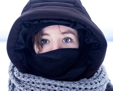 Photo couleur d'une femme portant une veste noire et un foulard autour du cou dans un pays froid