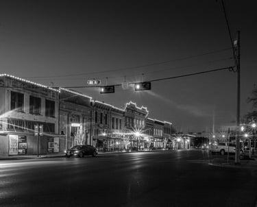 Night photo of Austin Ave in Georgetown, Texas, with it's historic buildings illuminated by streetlights