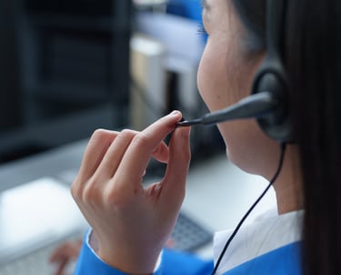 Mulher de costas com fone de ouvido e microfone fazendo atendimento ao cliente