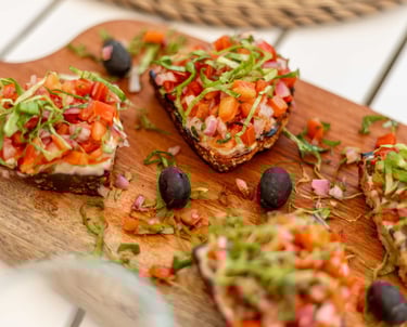 a wooden board with bruschetta appetizer and a glass of wine